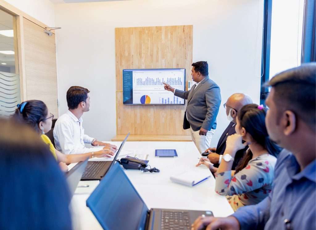 7 People Meeting With A Man Presenting A Powerpoint